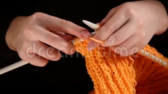 女人坐着编织橙色的围巾大的针织在视频的预览图