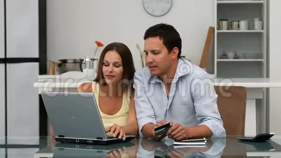 快乐的一对夫妇在网上看着他们的账户坐在桌子旁视频的预览图