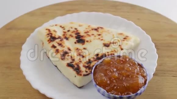 木板上的白色盘子里放着带有浆果酱的拉普兰奶酪视频的预览图