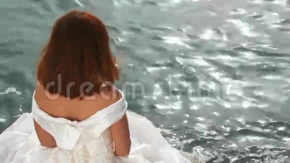穿着白衣服坐在石头上的年轻美女视频的预览图