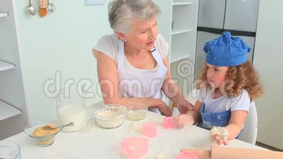 可爱的卷发女孩和她的祖母一起烘焙视频的预览图
