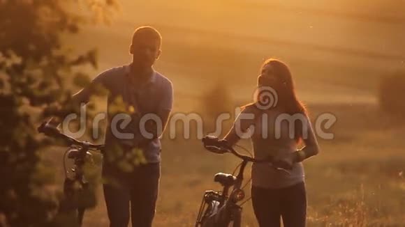 日落时骑自行车的漂亮夫妇视频的预览图