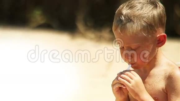 小男孩在阳光明媚的海滩上吃酸奶视频的预览图