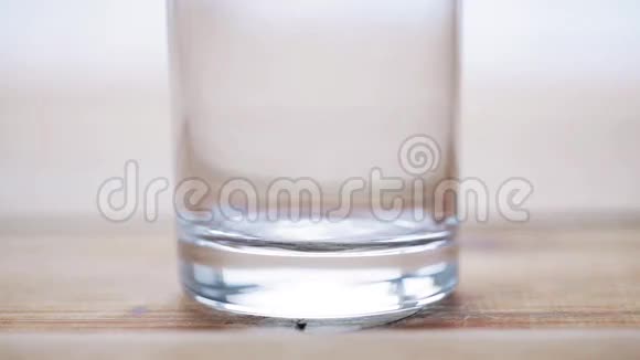 用手将牛奶倒入木制桌子上的空玻璃中视频的预览图