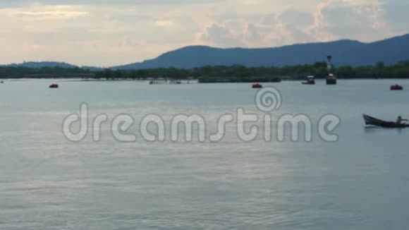 模糊的无法辨认的渔夫他的渔船穿越蓝色的海洋在山前的背景视频的预览图