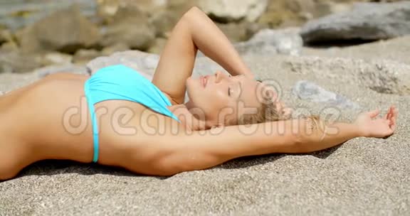 穿比基尼的女人在沙滩上晒太阳视频的预览图