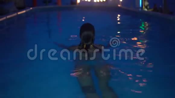 快乐的女人晚上在豪华游泳池放松游泳池女子4k视频视频的预览图