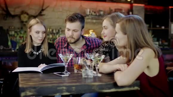 快乐的年轻人坐在酒吧里看菜单卡视频的预览图