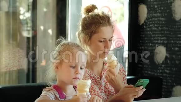 一位年轻的母亲和她的小女儿慢慢地在餐馆里度过时光吃冰淇淋视频的预览图