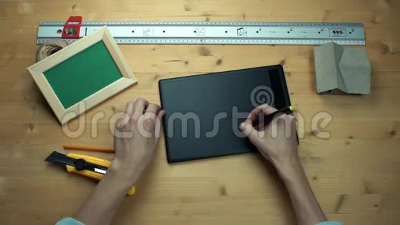 顶部视图男性手使用数字图形平板电脑在木制桌子视频的预览图