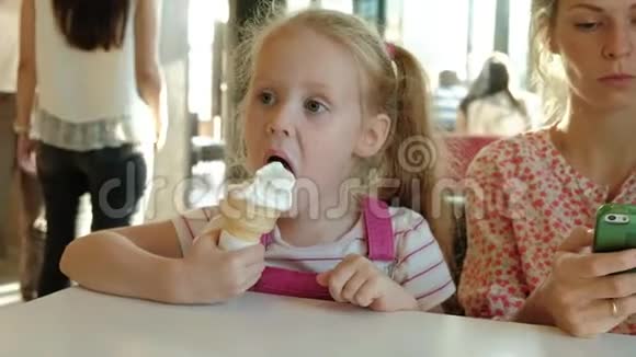 一位年轻的母亲和她的小女儿慢慢地在餐馆里度过时光吃冰淇淋视频的预览图