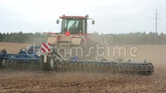 一辆农用拖拉机犁一块田从摄像机上移动泥土尘埃视频的预览图