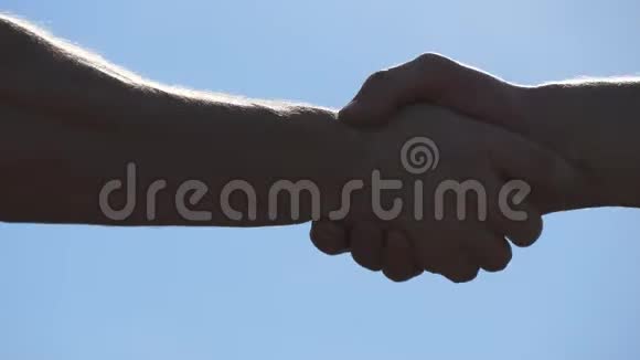 在蓝天背景下友好地握手两个无法辨认的肌肉白人男子户外男性手臂晃动二视频的预览图
