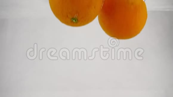 橘子掉进水里有气泡慢动作录像孤立的白色背景上的水果视频的预览图