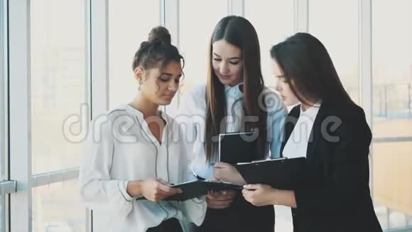 集团友好的三个多民族商人站在办公大厅拿着文件学习财务报告视频的预览图