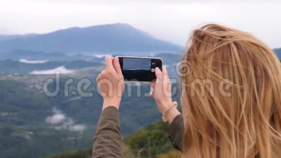 山顶的年轻女子慢镜头自拍年轻的徒步旅行者女人拍照视频的预览图