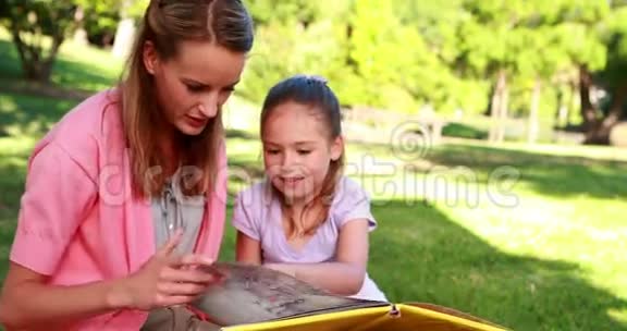 小女孩和妈妈在公园里读故事书视频的预览图