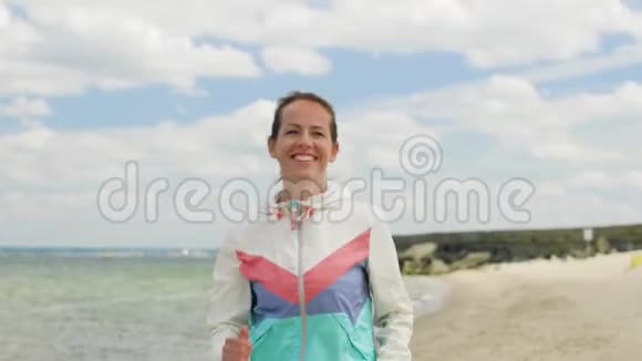 微笑的女人沿着海滩奔跑视频的预览图