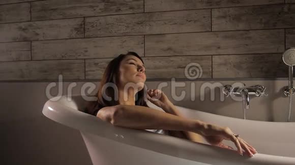 美丽的女人躺在白色浴缸里视频的预览图