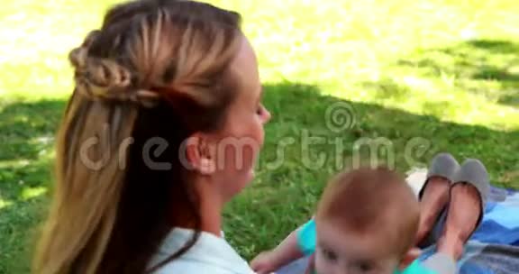 漂亮的妈妈在野餐毯上玩她可爱的小儿子视频的预览图
