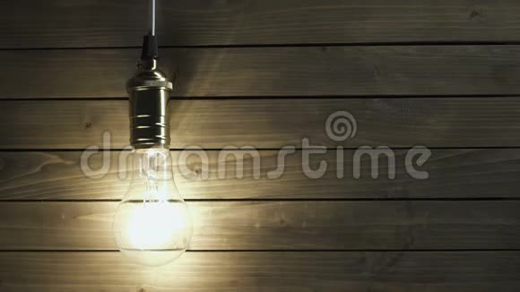 灯泡慢慢地亮起很快地闪烁在木头上的背景上视频的预览图