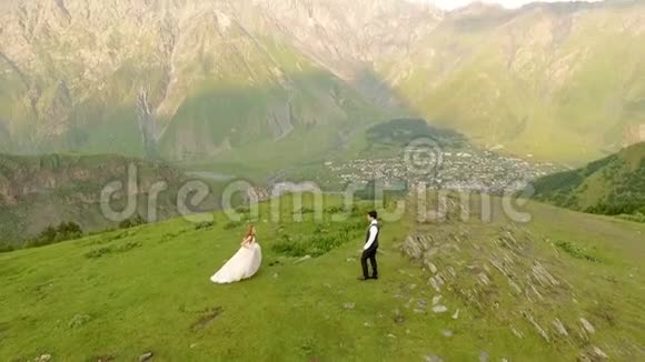 高山背景下幸福新郎新娘的鸟瞰图视频的预览图