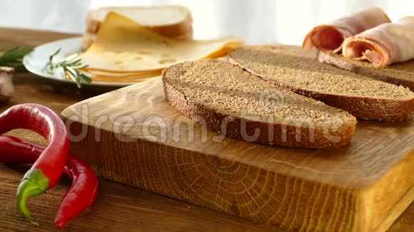 夹着培根和奶酪的三明治黑面包配培根和香料盘子上有洞的奶酪切成薄片的猪肉视频的预览图