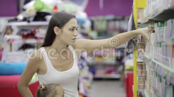 年轻女子带着可爱的女儿在购物中心选择婴儿食品视频的预览图