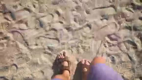 一个人穿着拖鞋走在海边的沙滩上视频的预览图