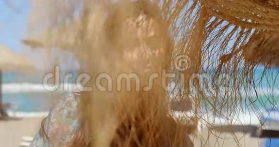 在沙滩伞旁微笑的美丽少女视频的预览图