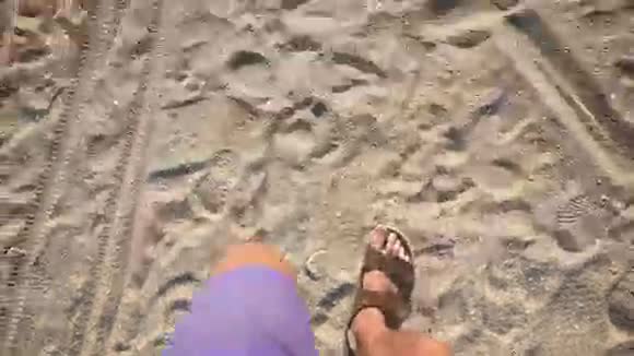 一个人穿着拖鞋走在海边的沙滩上视频的预览图