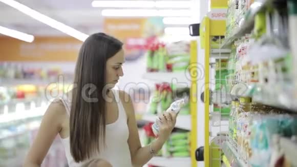 年轻女子带着可爱的女儿在杂货店购物中心挑选商品视频的预览图