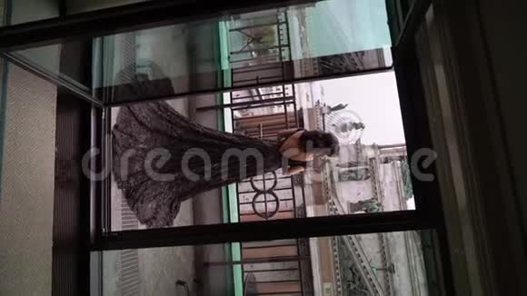 年轻的黑发女人穿着黑色豪华礼服住在城市的阳台上视频的预览图