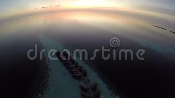 鸟瞰日落海面和豪华的水上别墅热带岛屿度假胜地马尔代夫视频的预览图