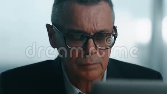 老商人在现代办公室里用电脑工作4他摘下眼镜对着屏幕看视频的预览图