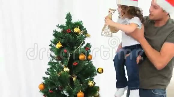 父亲帮助女儿装饰圣诞树视频的预览图