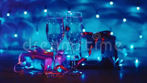 提供圣诞礼物和新年礼物两杯带蓝色花环的香槟视频的预览图