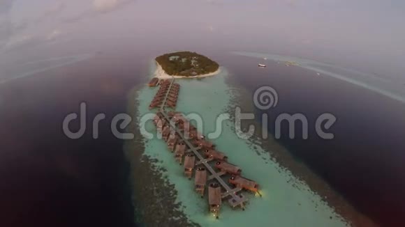鸟瞰日落海面和豪华的水上别墅热带岛屿度假胜地马尔代夫视频的预览图