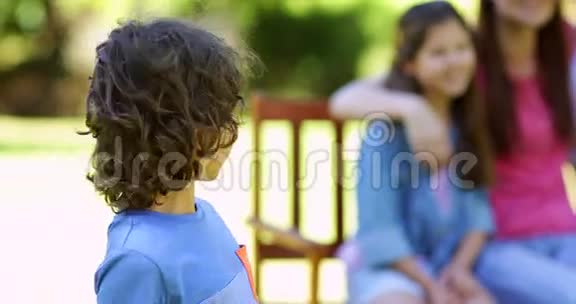 小男孩和一家人在公园的长椅上对着镜头挥手视频的预览图