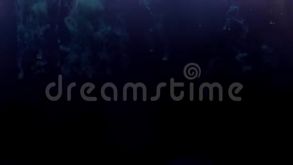 蓝色墨水从上面滴下来混合在黑暗的水中轻轻地在黑色背景下旋转视频的预览图