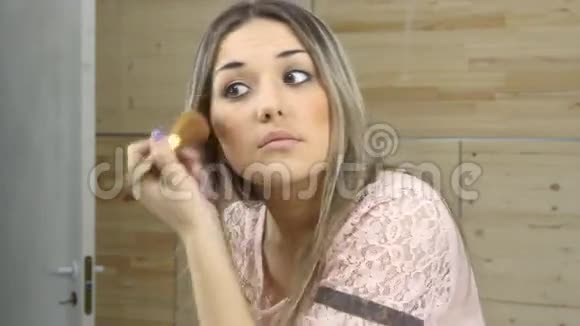 女孩照镜子用大刷子涂化妆品视频的预览图