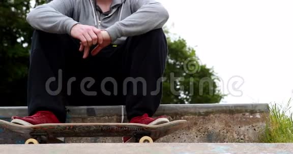 坐在户外溜冰场的年轻滑板运动员视频的预览图