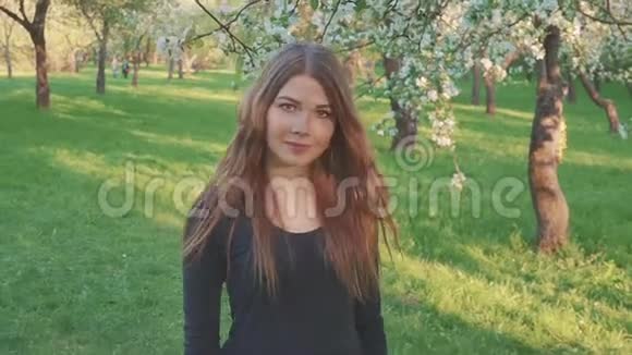 年轻的女人走在苹果园里春天的花白了傍晚水果中一个美丽女孩的肖像视频的预览图