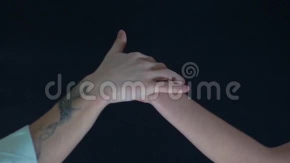 在黑色背景下男人和女人的手视频的预览图