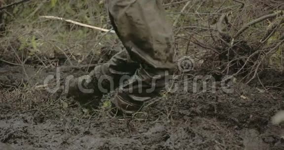一个穿靴子的人走在厚厚的泥上视频的预览图