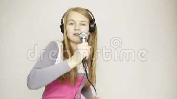 年轻女孩听着耳机里的音乐拿着麦克风唱歌和有趣的舞蹈视频的预览图
