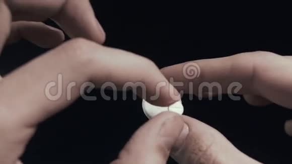 男人检查小药丸和大药丸的手近距离拍摄黑色背景POV视频的预览图