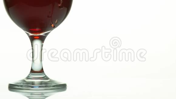 红酒倒在玻璃旁边白色背景下视频的预览图