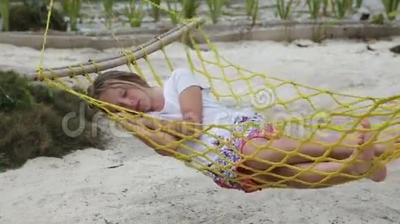 年轻女孩在海边的吊床上放松视频的预览图