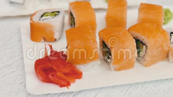 美味的寿司三文鱼奶酪芥末粉红色生姜酱油在时尚的白色木制背景上视频的预览图